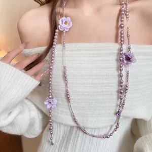 Detailed close-up of elegant purple pearl and fabric flower tassel necklace on model