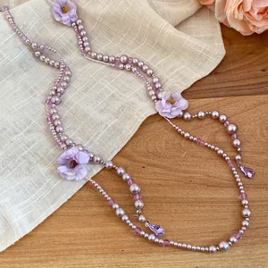 Detail view of purple pearl necklace with fabric flowers and purple crystal teardrops.