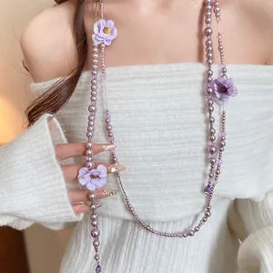 Close-up of elegant purple pearl necklace with delicate fabric flower accents