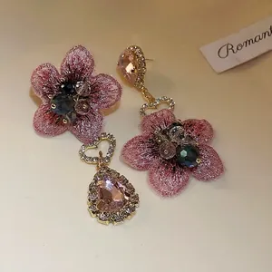 Boucles d'oreilles asymétriques fleurs brodées roses avec cristaux et cœurs dorés.