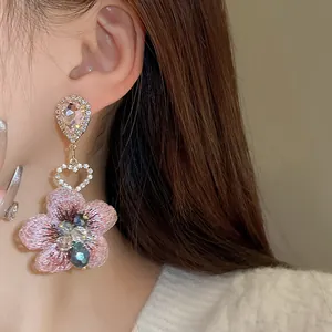 Gros plan d'élégantes boucles d'oreilles fleurs en cristal rose portées par un mannequin