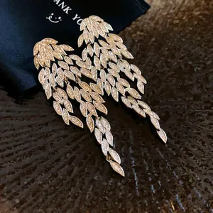 Close-up detail of silver needle long leaf fringe earrings with shimmering zircon stones