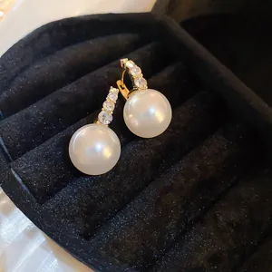 Close-up detail of elegant gold-toned earrings with crystals and large white pearls