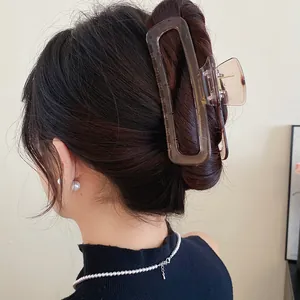 Détail de dos d'une grande pince à cheveux en acrylique ambrée maintenant un chignon haut