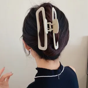 Détail d'une pince à cheveux minimaliste en acrylique crème sur cheveux foncés.