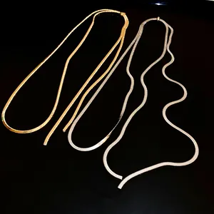 Dettaglio di lunghe collane a catena a serpente regolabili placcate oro e argento.