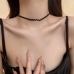 Macro detailed view of a black wavy lace choker necklace worn on a female model