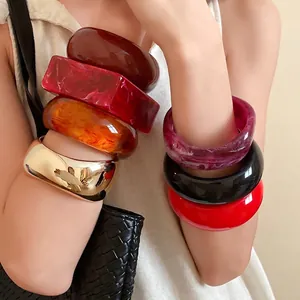 Stack of chunky resin geometric bangles in multiple colors worn by a model in style