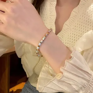 Hand wearing a colorful cylindrical beaded stretch bracelet with gold accents.