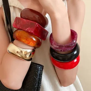 Detailed view of layered colorful resin geometric bangles and gold metal cuff