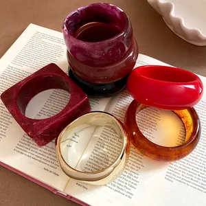 Close-up of assorted resin bangles with marble textures and bold colors on an open book