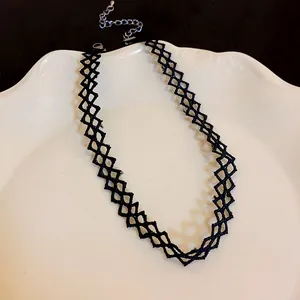 Macro view of a black lace choker necklace featuring a delicate woven mesh pattern on a white plate
