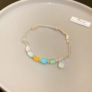 Close-up of colorful cylindrical beaded elastic bracelet with silver spacers and charm