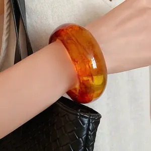 Detailed close-up of a chunky amber resin bangle showing unique internal textures