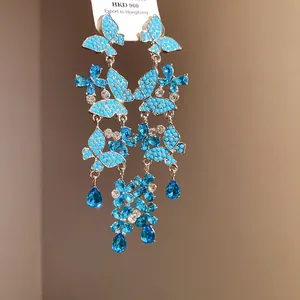 Detailed macro view of blue turquoise butterfly tassel earrings with crystal drops.