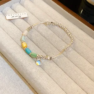 A detailed view of a colorful cylindrical elastic bracelet displayed in a soft jewelry tray