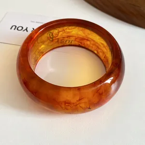 Macro detail of amber resin bangle with marble texture and warm translucent finish