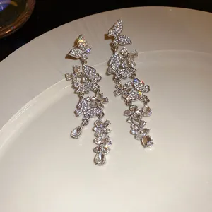 Detailed view of sparkling rhinestone butterfly tassel earrings on a white plate.