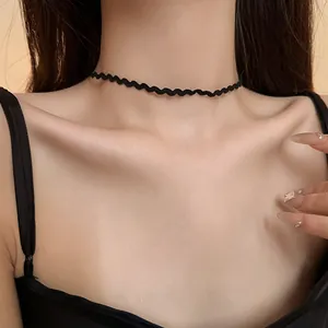 Detailed close-up view of a minimalist black wavy lace choker necklace on a woman's neck
