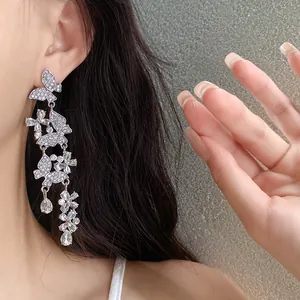 Detail view of silver tassel earrings featuring sparkly rhinestone butterflies and flowers