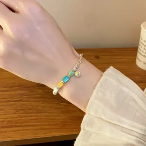 Close-up detail of a colorful cylindrical bead elastic bracelet on a woman's wrist