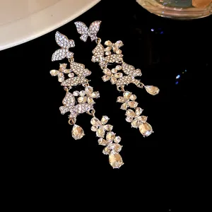 Detailed view of shimmering butterfly and floral crystal tassel earrings on black background