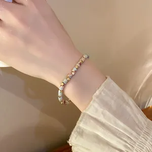 Close-up of a colorful cylindrical beaded elastic bracelet on a wrist with a ruffled sleeve