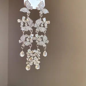 Detailed shot of sparkling butterfly and flower tassel earrings with clear zirconia stones