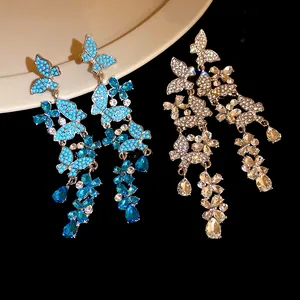 Close-up of butterfly and flower tassel earrings featuring blue and clear rhinestones