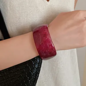 Detailed close-up of a thick translucent red resin bangle with marble texture on wrist