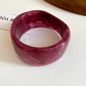 Detailed close-up view showing the rich marble pattern of a magenta resin bangle bracelet
