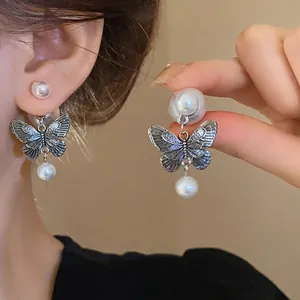 Vintage silver butterfly earrings with faux pearl drops for a chic and elegant look.