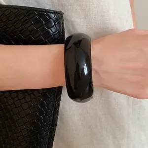 Detailed close-up of a minimalist chunky black resin bangle with high gloss finish