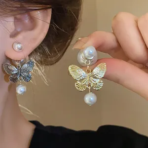 Close-up detail of butterfly and pearl earrings in gold and silver tones.