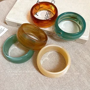 Braccialetti larghi in acrilico marmorizzato retrò, set colorato da donna su libro d'epoca