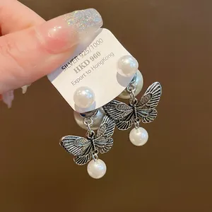 Detail shot of silver butterfly pearl earrings showing intricate wing patterns and luster