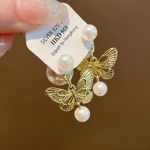 Detailed close-up of gold butterfly earrings with pearls and S925 silver post.