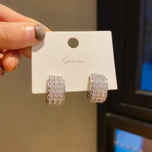 Close-up of sparkling diamond-encrusted silver hoop earrings on a white display card