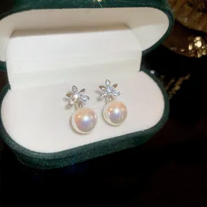 A detailed view of elegant silver flower stud earrings with iridescent pearl drop pendants