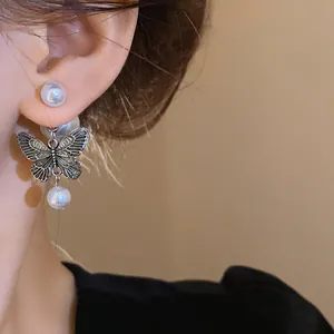 Close-up detail of vintage silver needle butterfly pearl earrings worn on model's ear