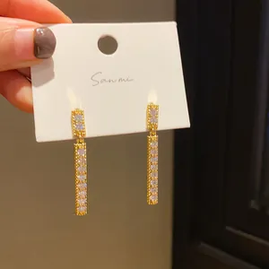 Close-up of gold bar earrings with sparkling white crystals on a display card.