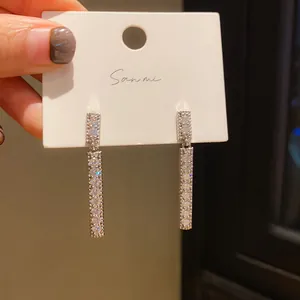 Close-up of silver-plated long bar earrings with pavé crystal inlay on display card.