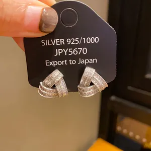Detailed view of knotted silver earrings with micro-pave cubic zirconia on display card