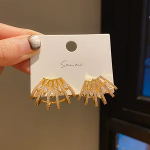 Detailed macro view of gold fan-shaped stud earrings with sparkling marquise crystal inlays
