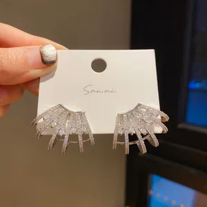 Detail view of silver earrings with sparkling stones on a white card holder.
