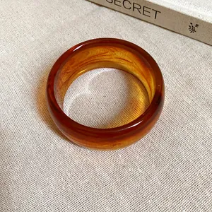 Primo piano di bracciale rigido in acrilico ambrato con elegante trama marmorizzata
