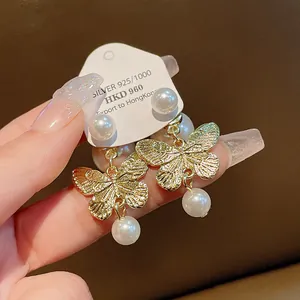 Macro detail of elegant gold-toned butterfly stud earrings featuring white pearls