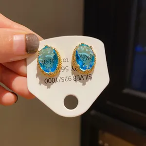 Close-up of vintage oval blue crystal earrings with ornate gold-tone settings.