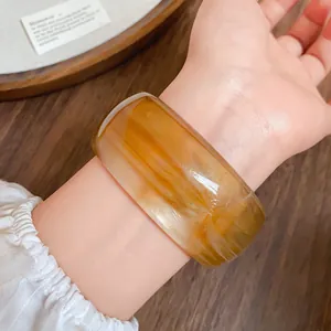 Primo piano di un ampio bracciale vintage in acrilico con venature ambrate al polso