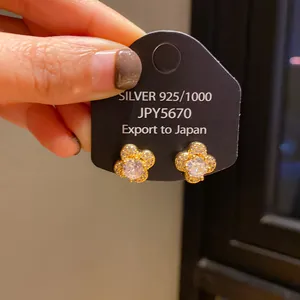 Detailed view of gold clover earrings with pavé crystals and central diamond on silver needle